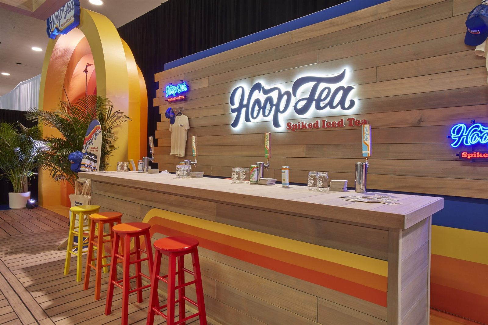 A colorful, fully custom-built branded exhibition stand with an archway and bar
